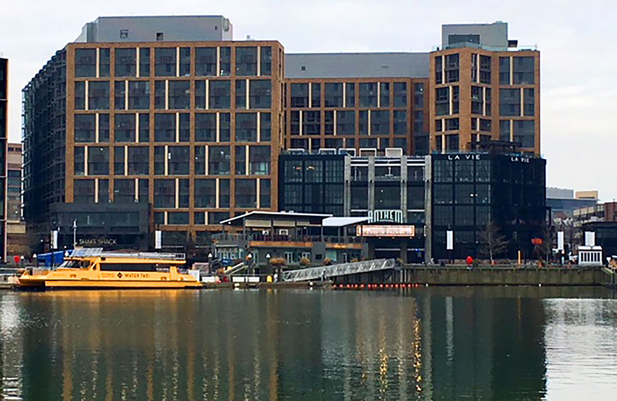 view of washington dc wharf with buildings in background and water in foreground