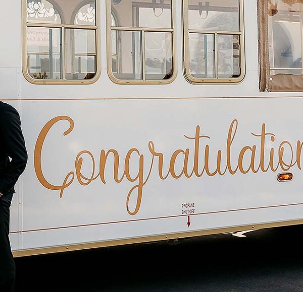 couple standing in front of San Diego Bella wedding trolley