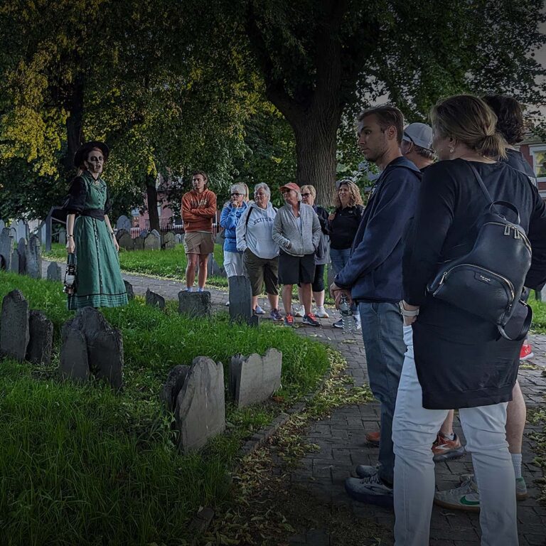 Ghosts & Gravestones Nightwalk tour guide and guests at burying ground