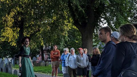 Ghosts & Gravestones Nightwalk tour guide and guests at burying ground