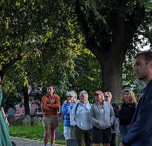 Ghosts & Gravestones Nightwalk tour guide and guests at burying ground