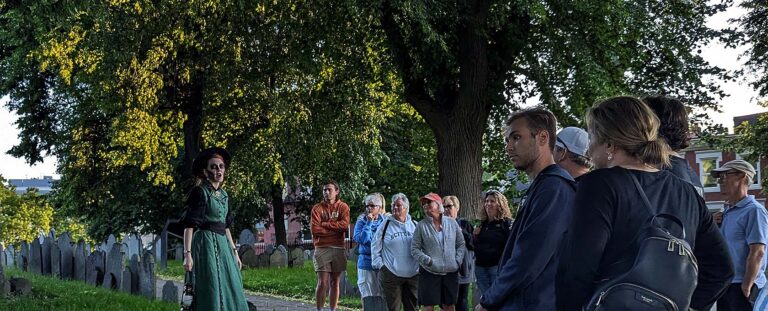 Ghosts & Gravestones Nightwalk tour guide and guests at burying ground